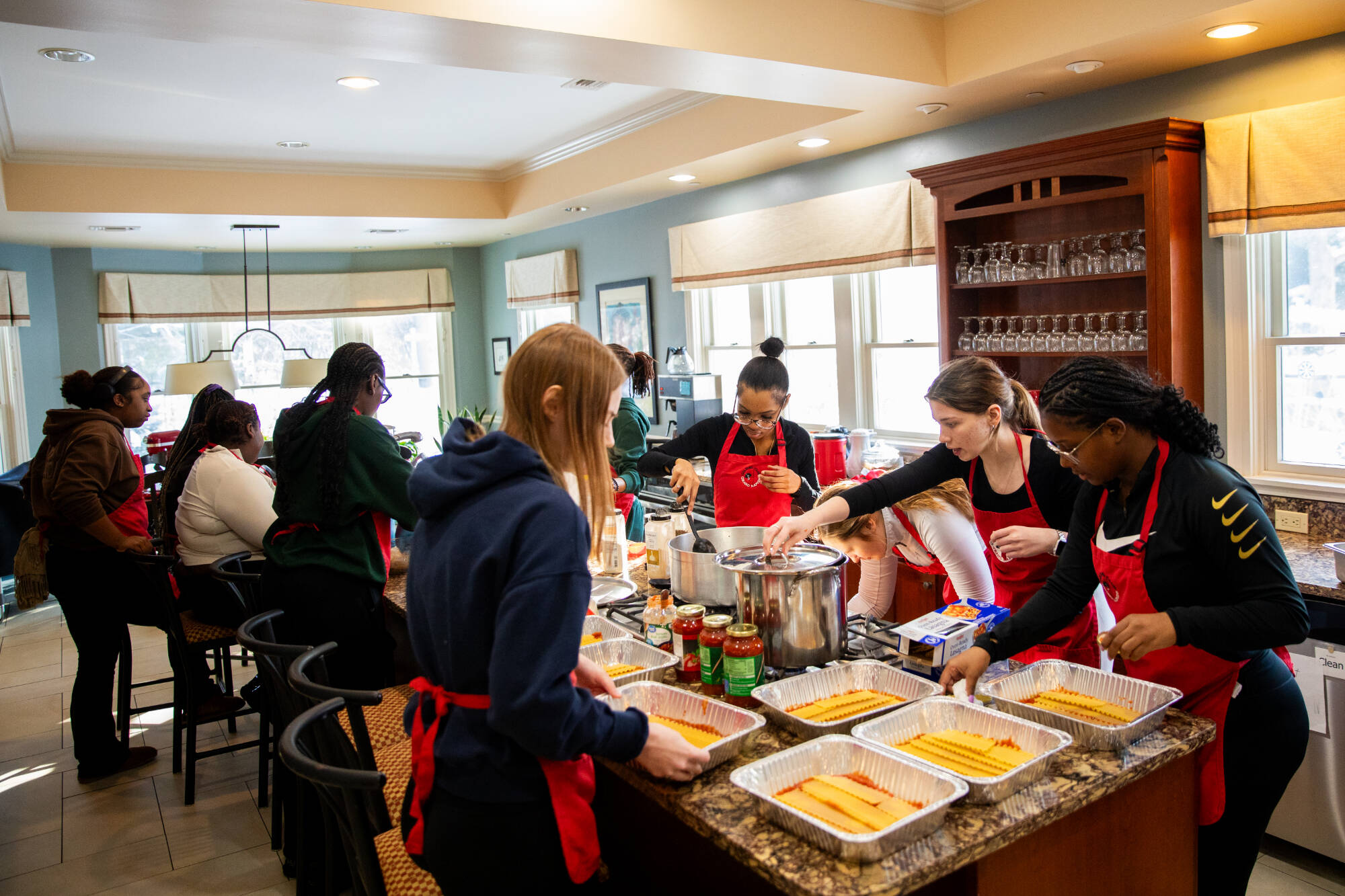 many individuals meeting around a table, one side of folks serving food to the other side of folks